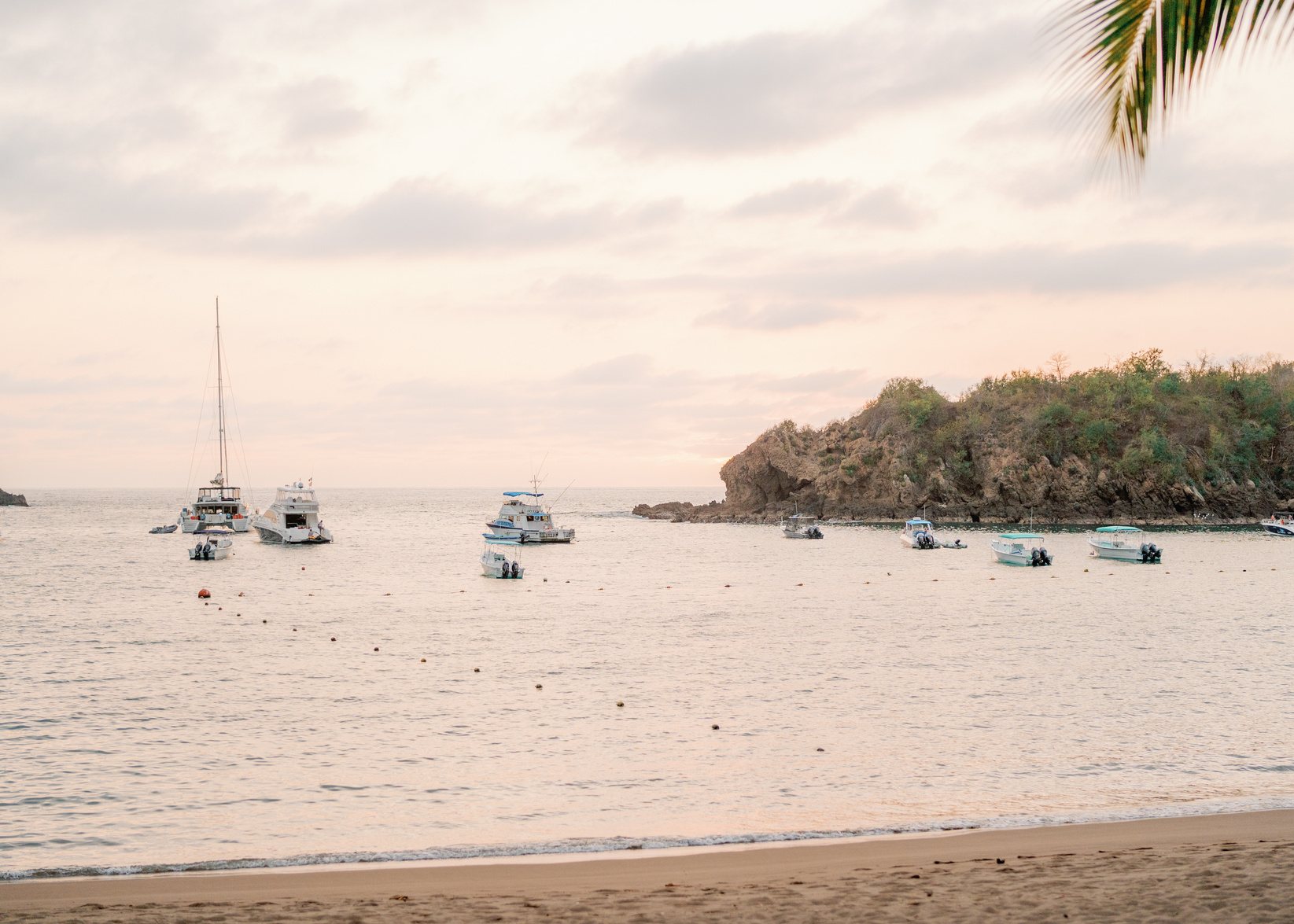 Boats moored off a quiet beach at dusk.